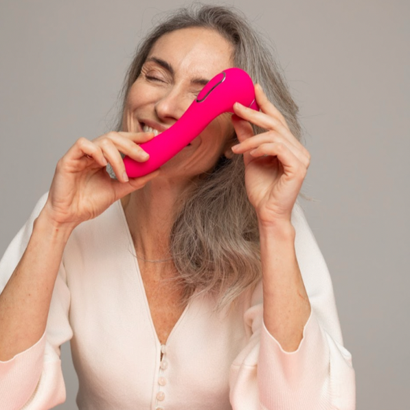 Pink dual stimulation toy from VIVA held by a smiling woman, showcasing a sleek design for intimate pleasure.