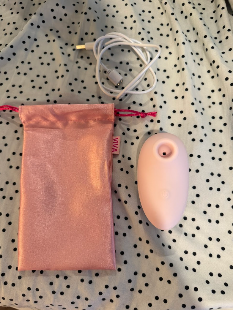 Pink silicone personal massager with USB charging cable and satin storage pouch.