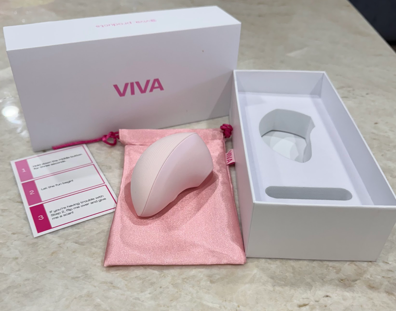 Pink ergonomic massager with storage pouch and instruction card, displayed beside packaging.