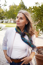 Light gray blazer over a white top, paired with a blue and green silk scarf.